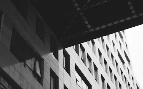 Black and white photo of a modern building facade with sharp shadows and gradients.
