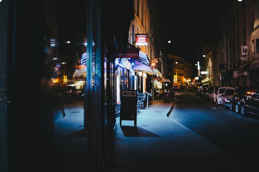 carros estacionados em frente às lojas durante a noite