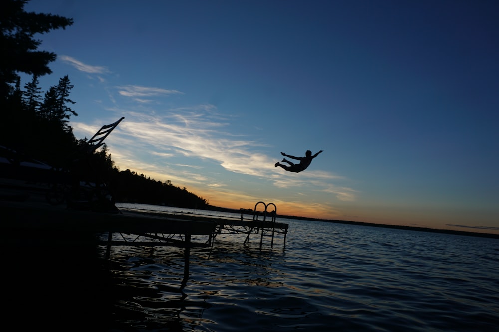silhouette of person diving on water