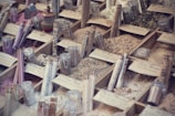 A display of various types of salts and spices organized in wooden boxes, with each section labeled. Glass jars and test tubes filled with different colored contents are placed among the boxes, showcasing a variety of textures and colors, from pink to green to white.