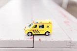 yellow car toy on white surface