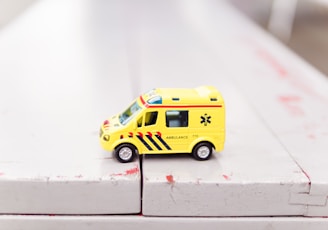 yellow car toy on white surface