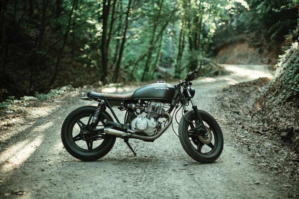 motorcycle parks on road between trees