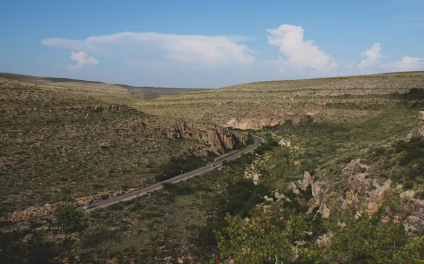 A scenic shot of a dusty road winding through rugged hills during a Safarnama road trip.