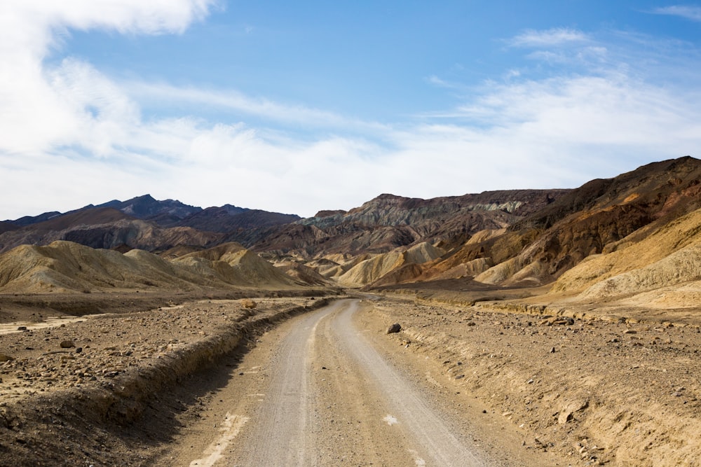 gray asphalt road near mountains under blue sky