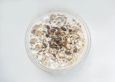 A bowl of wholesome dalia porridge topped with nuts and seeds.