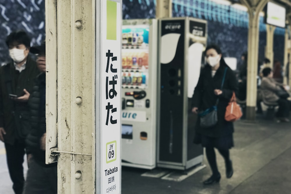 woman standing beside vending machine