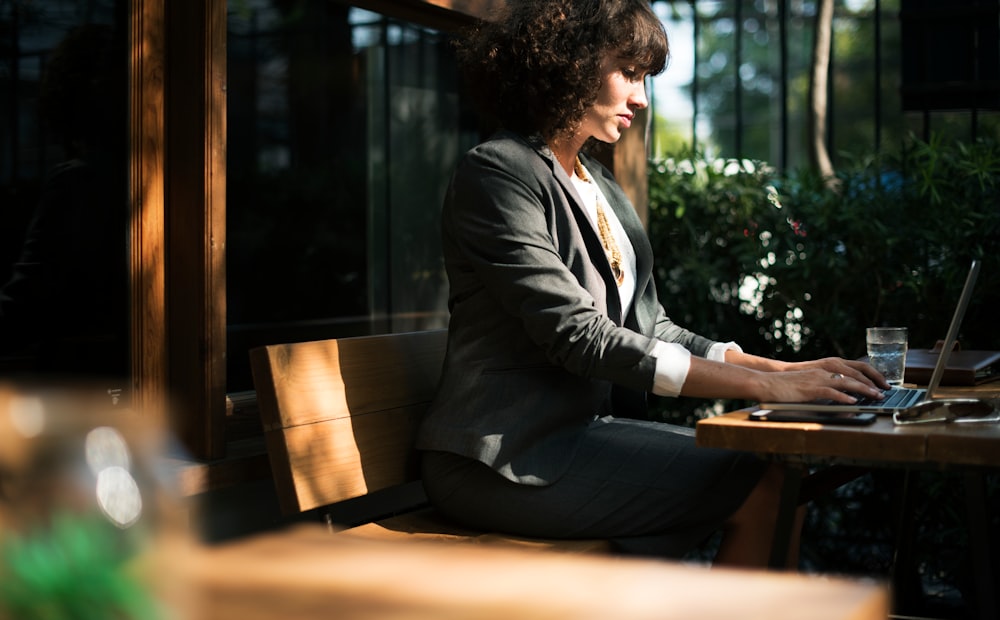 A businesswoman sitting at an outside table and typing on a table