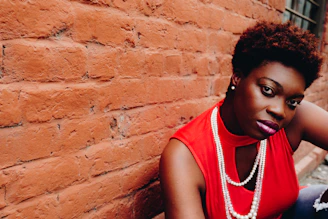 woman sitting near red brick wall