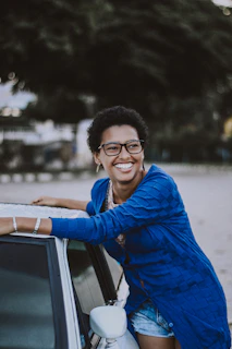 A smiling customer standing beside their car with a freshly repaired windshield