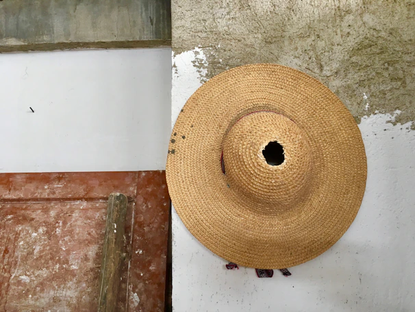 A cinematic photo of a straw hat hanging on a weathered barn door, bathed in soft natural light.