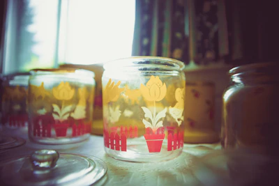Brightly colored stacked ceramic jars surrounded by fresh flowers and soft natural light.