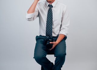 man in white dress shirt and blue pants holding DSLR camera