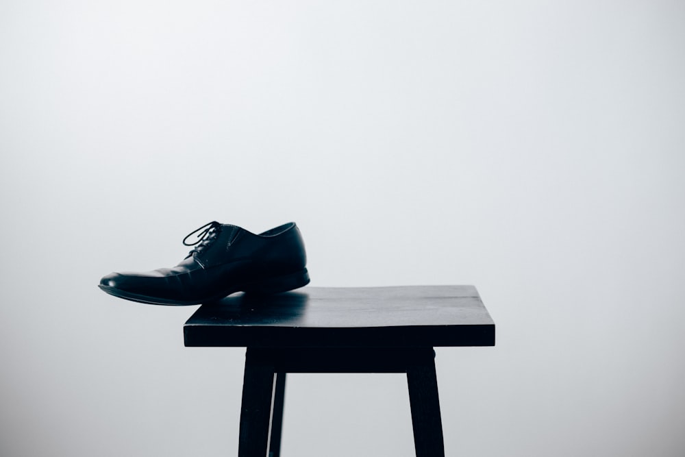 sapato de couro preto do vestido na mesa de madeira preta