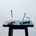 timelaps photo of assorted-color pen on brown wooden saddle stool chair