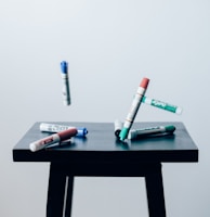 timelaps photo of assorted-color pen on brown wooden saddle stool chair