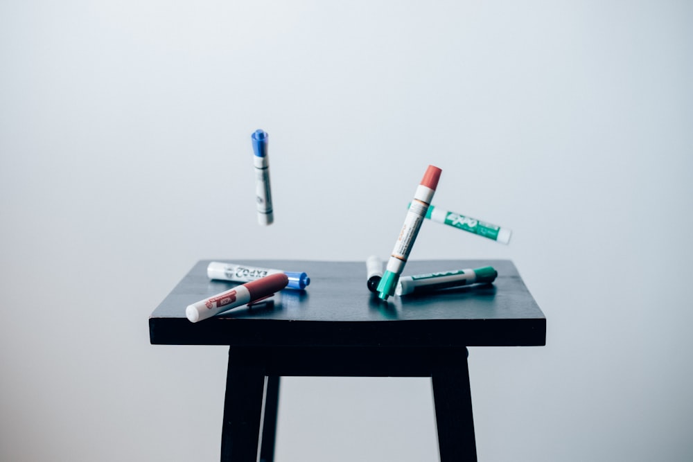 timelaps photo of assorted-color pen on brown wooden saddle stool chair