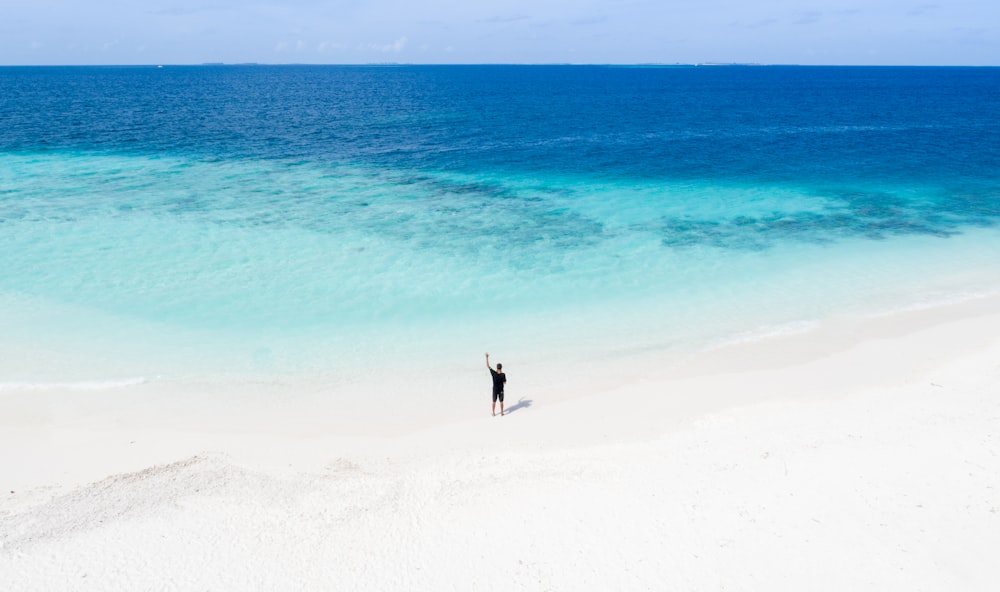 person standing on white sand beach