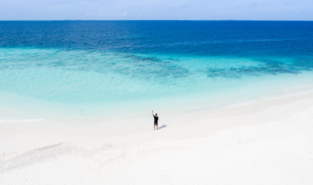 Person, die am weißen Sandstrand steht