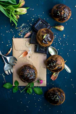 A beautifully arranged assortment of baked goods including chocolate cake, muffins, and cinnamon rolls on a rustic wooden table.