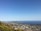 A panoramic view of a coastal city with green parks and clear blue water.