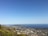 A panoramic view of a coastal city with green parks and clear blue water.