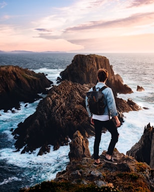 photography poses for men,how to photograph after hiking towards the roaring ocean with no idea what was ahead of us, this view opened up before our eyes.; man standing near cliff looking at body of water during daytime