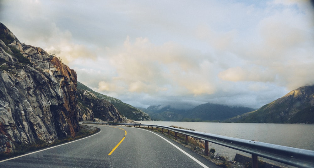 body of water beside of concrete road and mountain