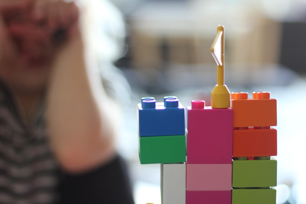 a woman sitting at a table next to a building made out of legos