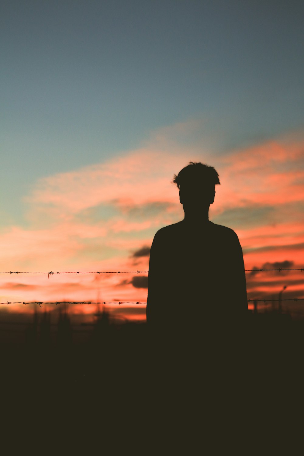 silhouette of man standing in front of fence