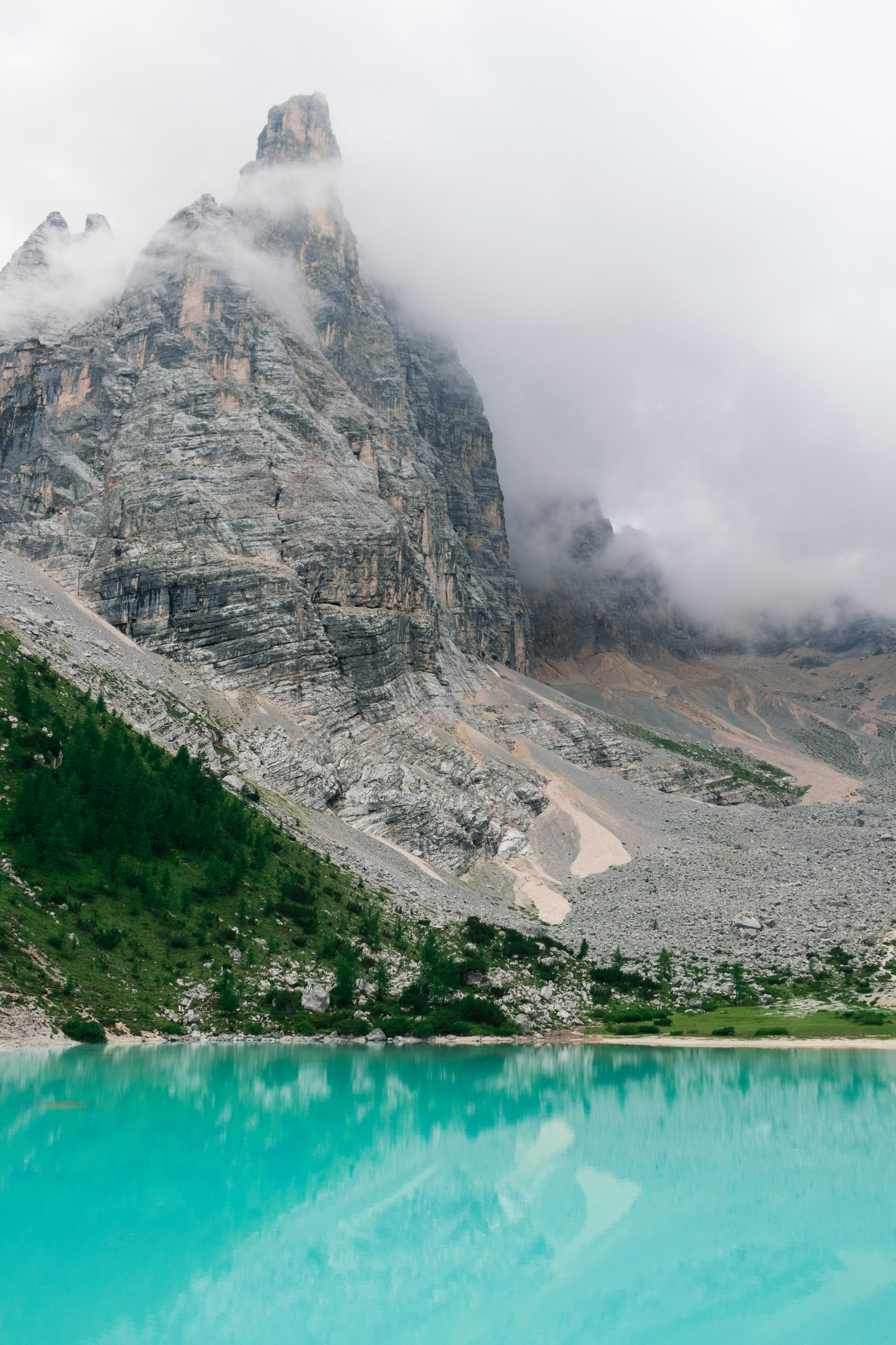 body of water at the foot of the mountain surrounded by clouds