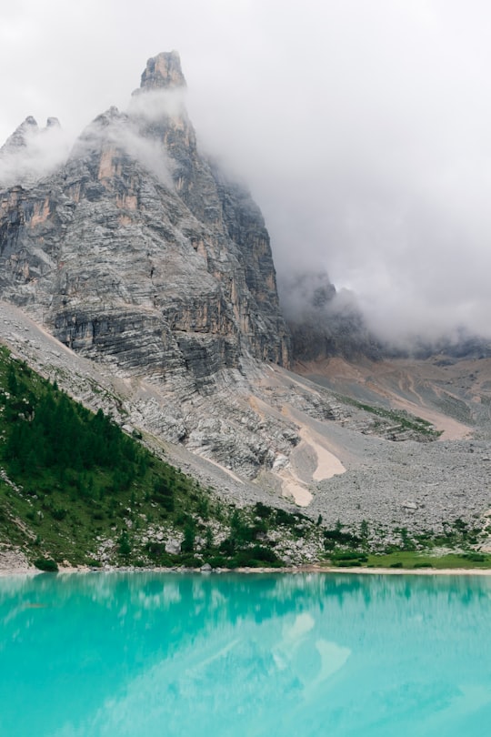 body of water at the foot of the mountain surrounded by clouds in Sorapiss Italy