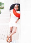 smiling girl in white shirt and shorts wearing red scarf during daytime