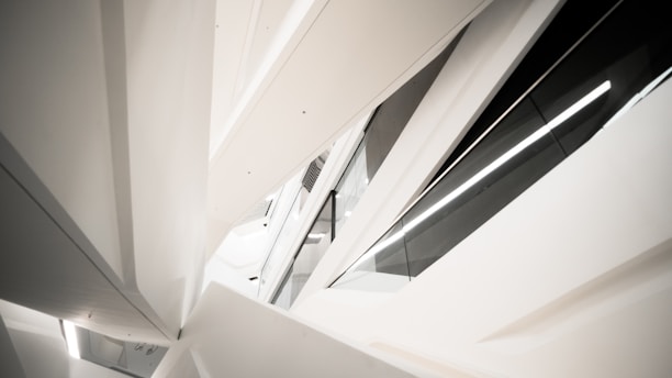 A modern architectural structure with angular, geometric shapes and sleek lines. The design features contrasting elements of white and black surfaces, creating a futuristic and abstract visual appearance.