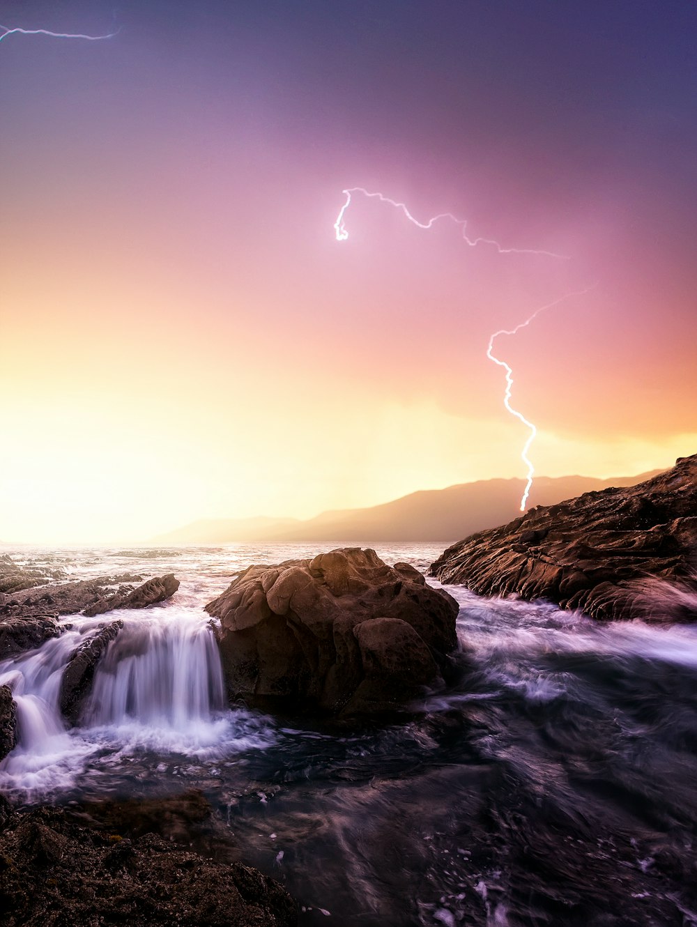 rock formation near sea under thunder light