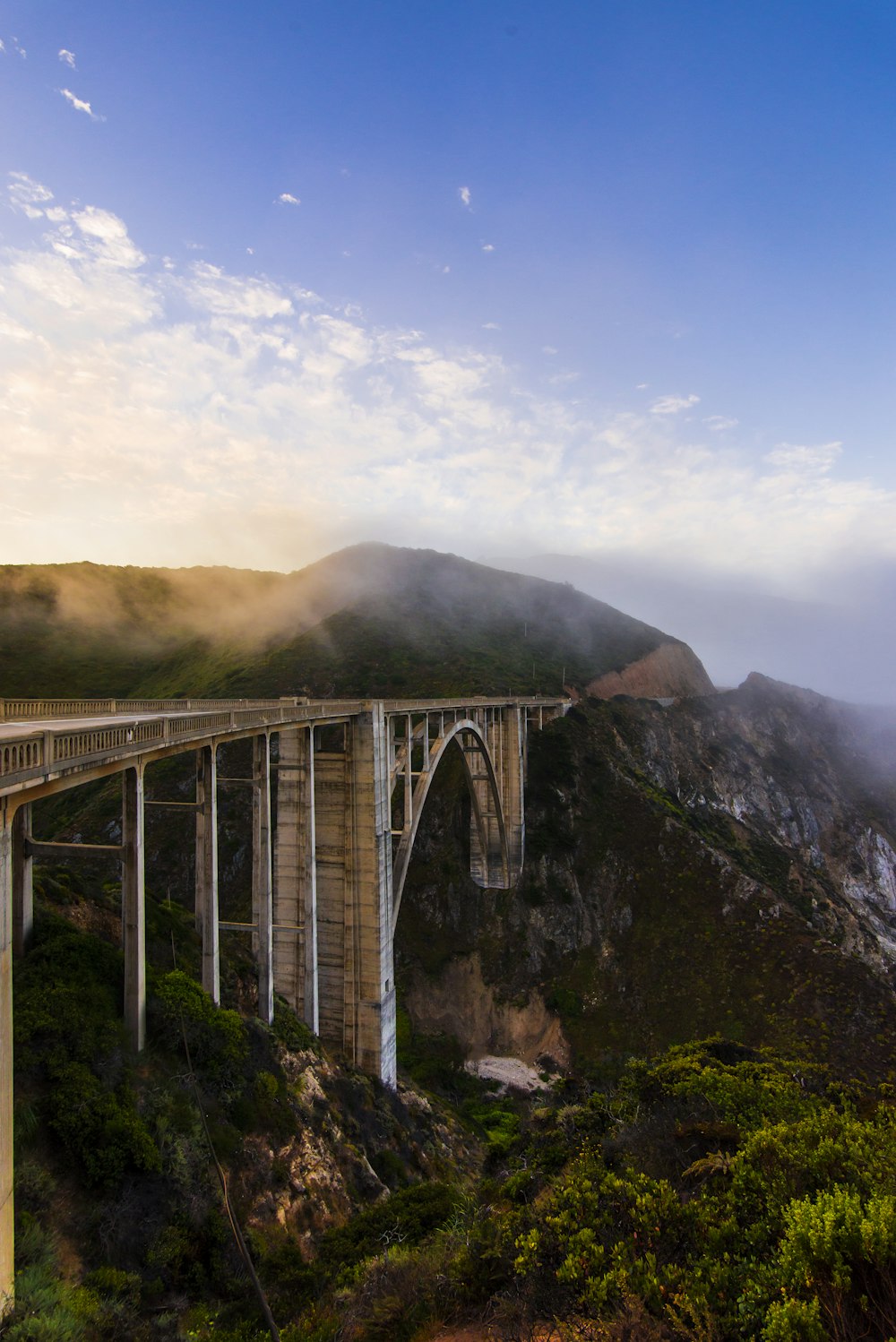 gray concrete bridge over green mountains during daytime