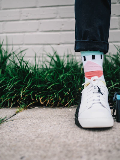 Colorful athletic sock paired with a white sneaker on grass