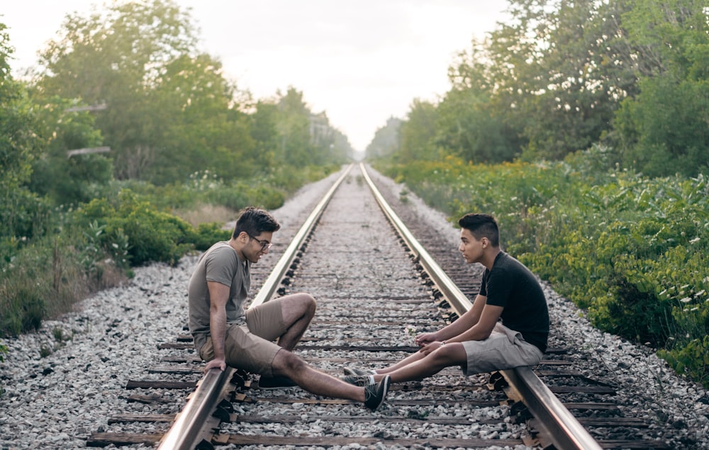 2 personas sentadas en los rieles del tren durante el día