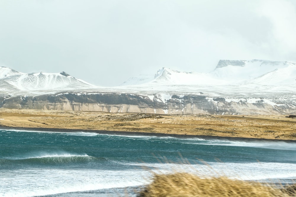 white and brown mountains beside body of water