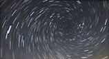 A long-exposure photograph of the night sky capturing the circular trails of stars rotating around the celestial pole.