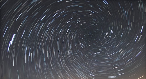 A long-exposure photograph of the night sky capturing the circular trails of stars rotating around the celestial pole.