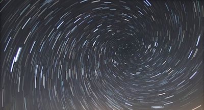 A long-exposure photograph of the night sky capturing the circular trails of stars rotating around the celestial pole.