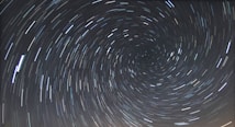 A long-exposure photograph of the night sky capturing the circular trails of stars rotating around the celestial pole.
