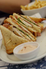 Close-up of the Club House sandwich showcasing layers of turkey, bacon, and melted cheese on golden bread.