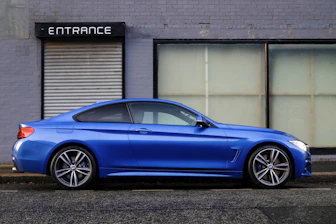 blue coupe beside gray house
