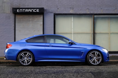 blue coupe beside gray house