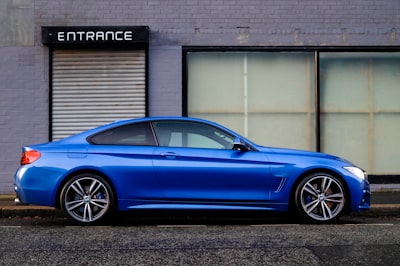 blue coupe beside gray house