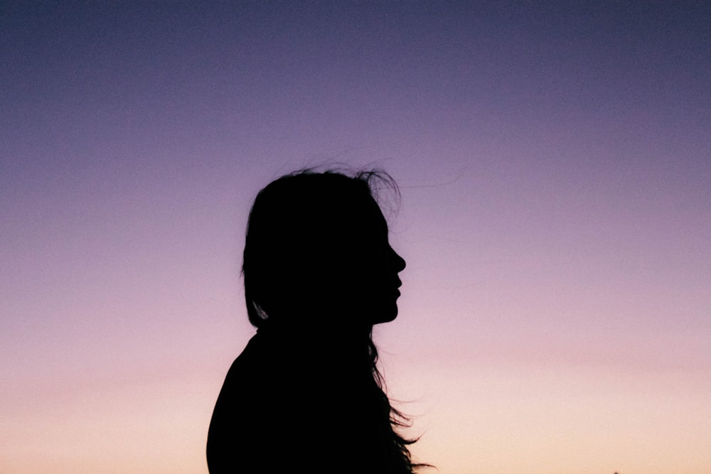 Silhouette of a woman standing alone at sunset
