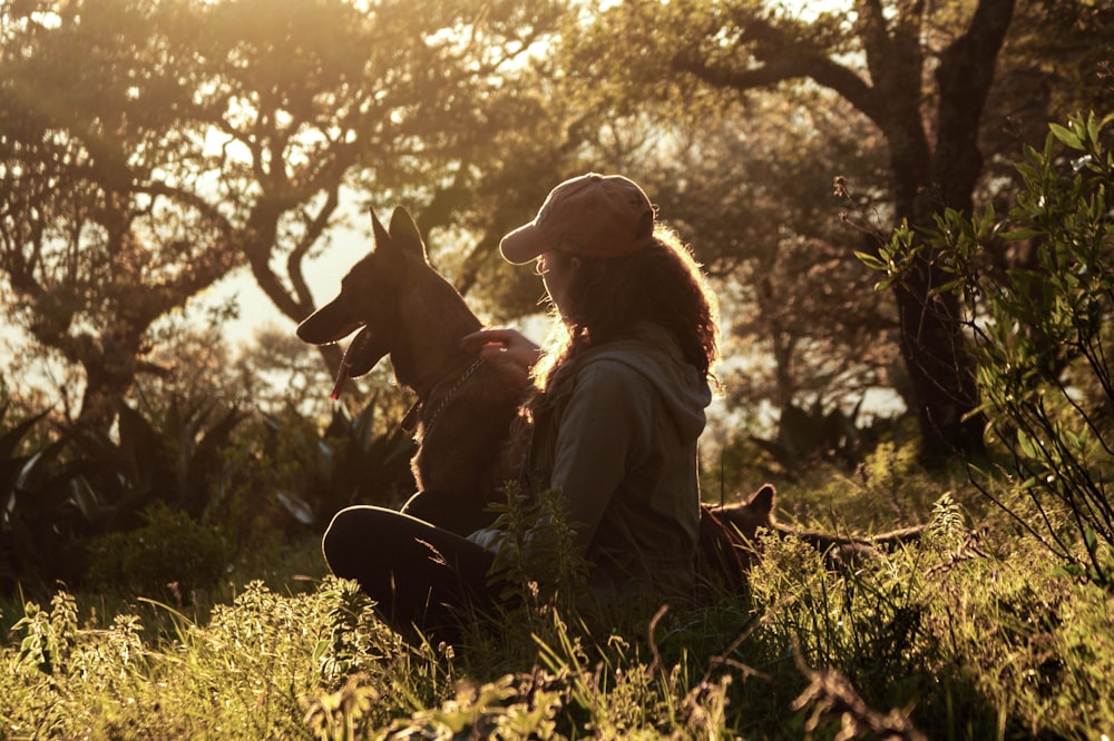 woman and dog sitting on grass field