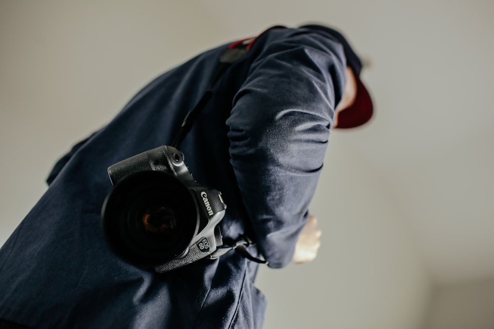 man carrying a black Canon DSLR camera